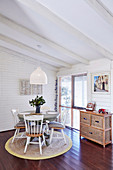 Round table with wooden chairs on carpet in dining area with white wood paneling