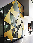 Geometrische Formen in Gold an der Glaswand zum Treppenhaus
