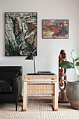 Side table, leather sofa and sculpture below two abstract paintings