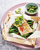 Fish fillet on green beans in parchment paper