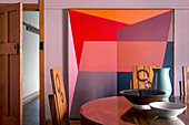 Vase und Schalen auf dem Esstisch vor grafischem Bild in Rottönen