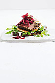 Open rye bread topped with lamb, haloumi, and beetroot salad