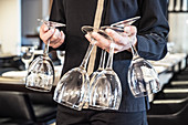 A waiter carrying wine glasses in the dining room of a restaurant