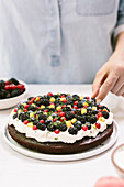 Decorating the top of a chocolate cake with berries