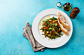Salad with quinoa, tomato, avocado, spinach and arugula on white plate on blue background