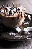 Large, glass mug of hot cocoa with marshmallows and chocolate drizzle