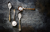 Variety of salts on vintage spoons on a rustic dark surface