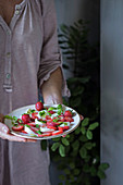 Woman holding strawberry salad with mozzarella cheese