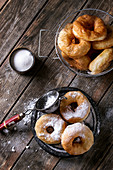 Homemade donuts with sugar powder on black serving board and in frying basket