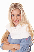 A young blonde woman wearing a blue jumper with a fluffy white jumper over her shoulders