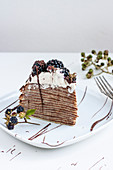 A slice of pancake cake with chocolate and blackberries