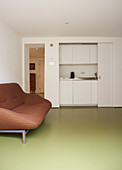 Brown sofa on green floor in front of kitchenette behind sliding doors
