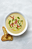 Potato and cheese soup with cress oil and bacon strips