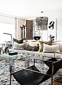 Cushions on sofa, glass coffee table and designer chair in bright living room