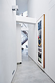 Painting in long, narrow, white corridor in architect-designed house