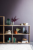 Open wooden shelf with decorative accessories against a violet wall