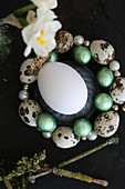 Egg in circlet of threaded quail eggs and beads
