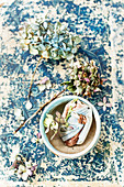 Getrocknete Hortensienblüten und Keramikfragment in Schale, auf altem Buchuntergrund