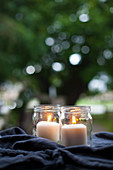 Two lit pillar candles in screw-top jars