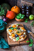 A mini pizza with chicken, pumpkin and thyme
