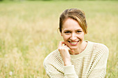 A young woman in a meadow wearing a a knitted jumper