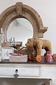 Old toy bear on wheels in front of oval mirror with wooden frame