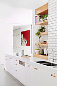 weiße Küchenzeile, darüber eingebaute Regalbretter aus Holz