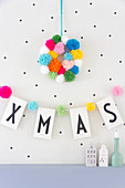 Wreath of colourful pompoms above Xmas garland