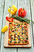 A pizza topped with peppers, garlic and rosemary