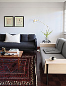 Two different sofas, side table, standard lamp and coffee table on rug in living room