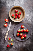 Erdbeeren in Schale, auf Teller und auf dunklem Metalluntergrund (Aufsicht)