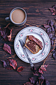 Slice of cake with chocolate ganache served on a dessert plate on dark rustic table