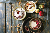 Variety bowls of milk cereal porridge with different additives, served with apples, berries and seeds