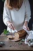 A woman slicing homemade bread in a kitchen