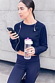 Woman holding water bottle and smartphone
