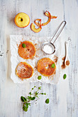 Battered apple rings with icing sugar, cinnamon and mint on a piece of paper