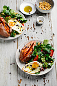 A mixed salad with a fried egg and roasted sweet potatoes