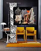 Yellow chairs and side table in front of photographic artwork and roll of wallpaper