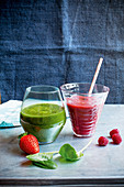 A red smoothie with raspberries and a green smoothie with spinach and strawberries