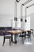 Pairs of pendant lamps above dining table in front of sofa