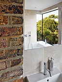 Modern bay window reflected in mirror in bathroom with brick wall