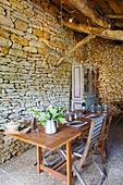 Set table in converted barn with stone wall