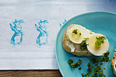 Baguette mit Ei auf österlicher Tischdecke dekoriert mit Hasenmotiven