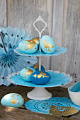 Blue Easter eggs decorated with gold leaf on cake stand