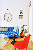 Glastisch, roter Stuhl und blaue Couch im Wohnzimmer