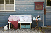 Various cushions with hand-sewn covers on bench outside wooden house