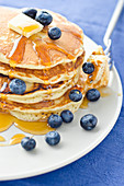 A Stack of Three Blueberry Pancakes with Maple Syrup and Orange Juice