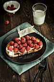 A sweet open sandwich with cream cheese, raspberries and maple syrup
