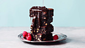 A stack of brownies with chocolate sauce and raspberries