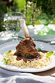 A lamb shank with couscous on a summery table outdoors